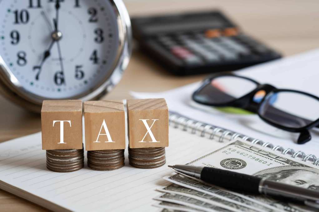 Tax image with clock, glasses, calculator, cash, and pen